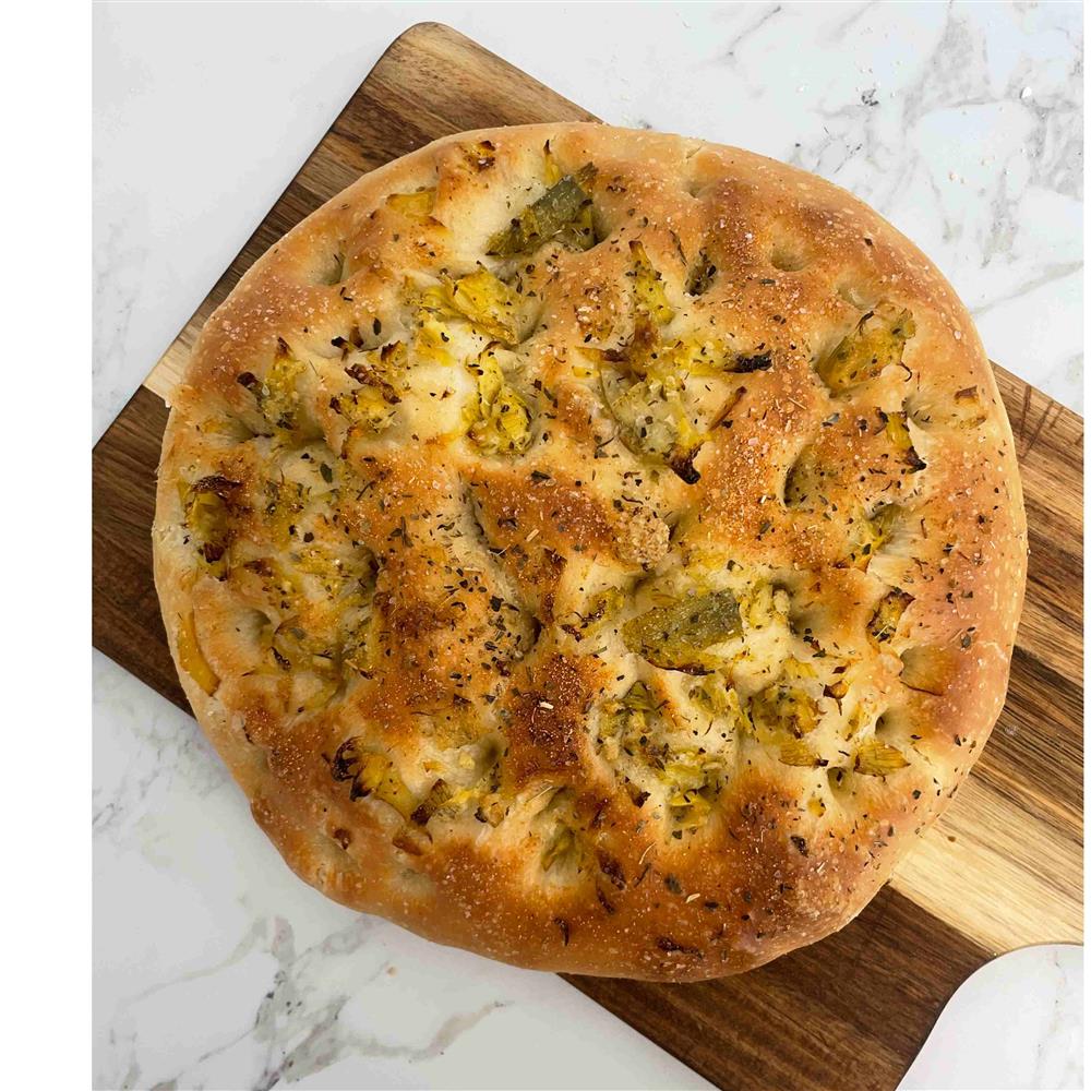 Round focaccia topped with herbs and artichoke pieces