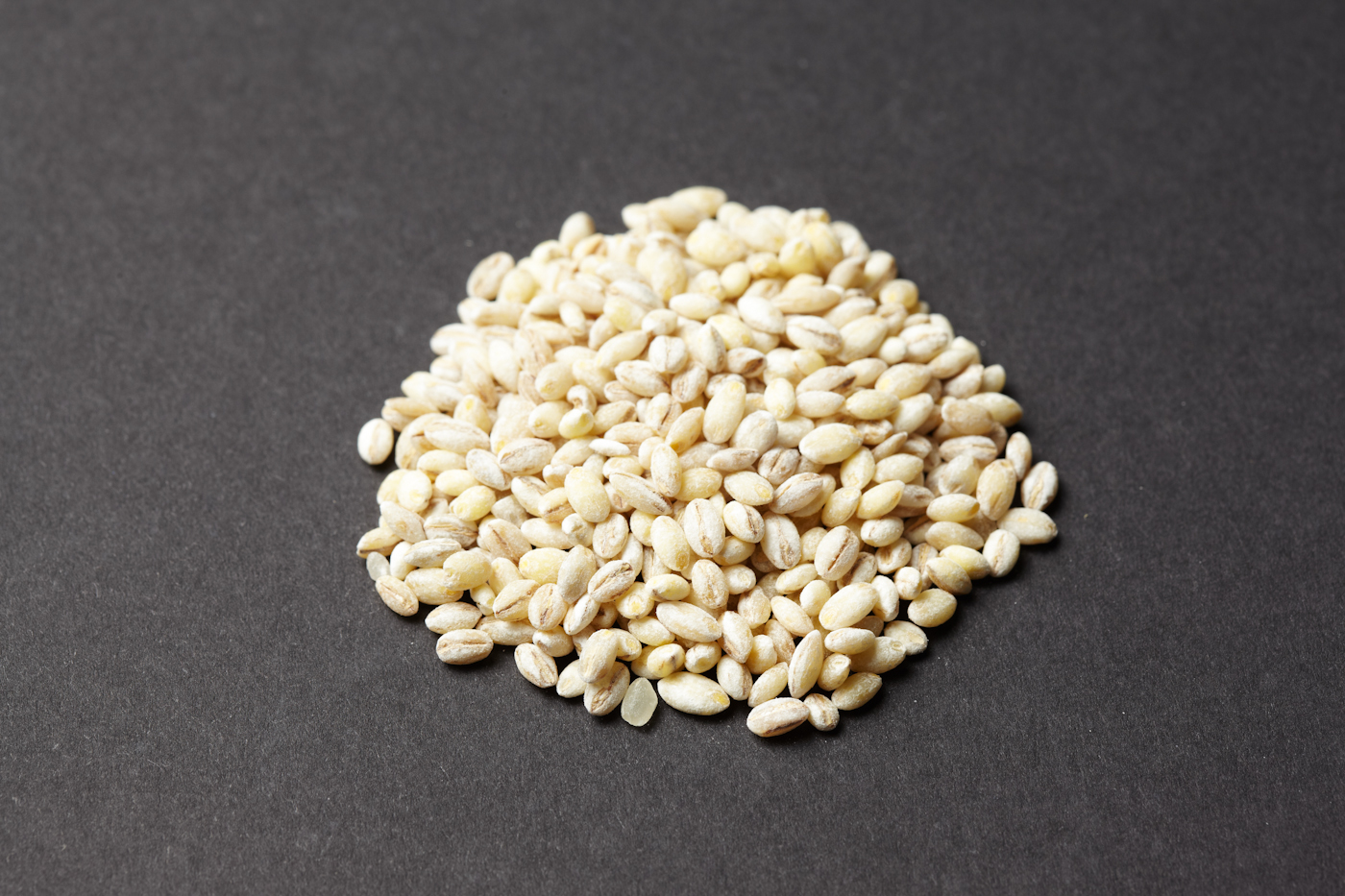Ingredient illustration: a small mound of dry barley grains on a dark surface, not the finished chicken dinner.