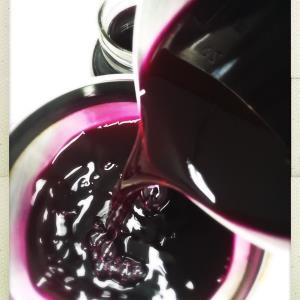 Dark red beet kvass being poured into a glass.