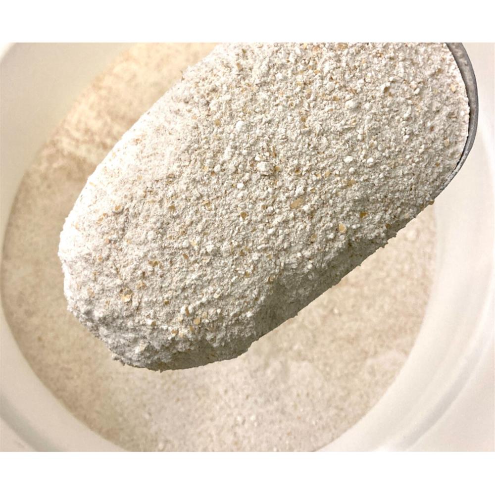 A spoonful of flour above a bowl of flour.