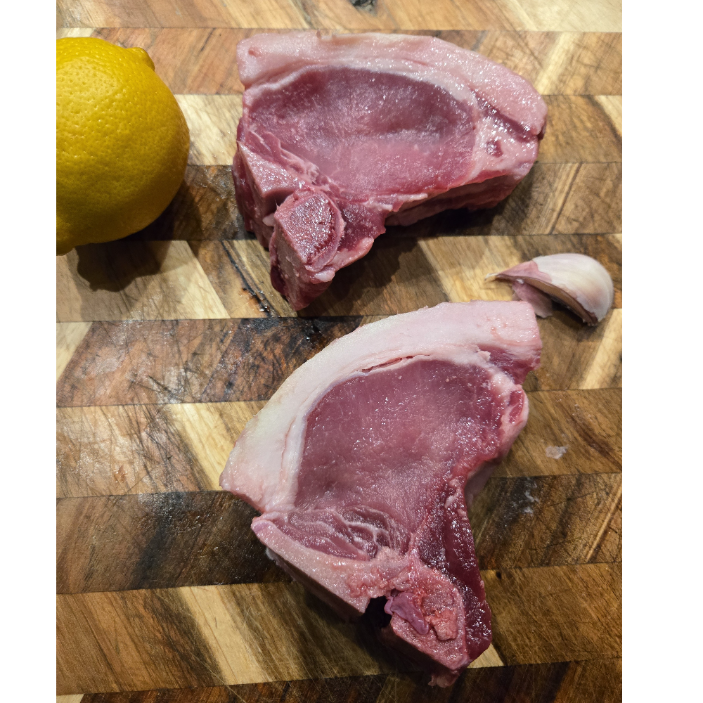 Raw bone-in pork chops on a board