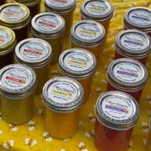Assorted Bee Happy honey jars with labeled metal lids.