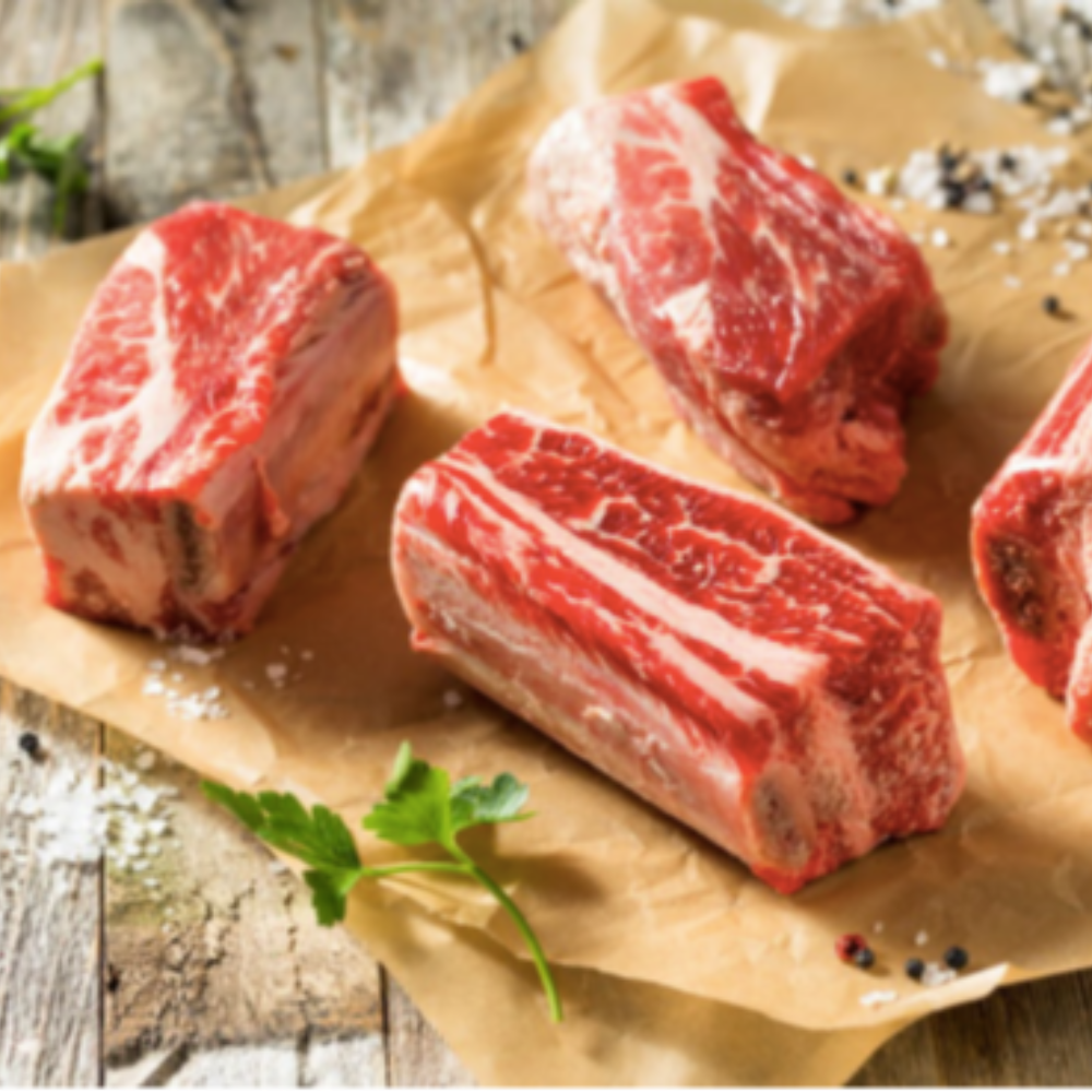 Raw beef short ribs on a wooden board