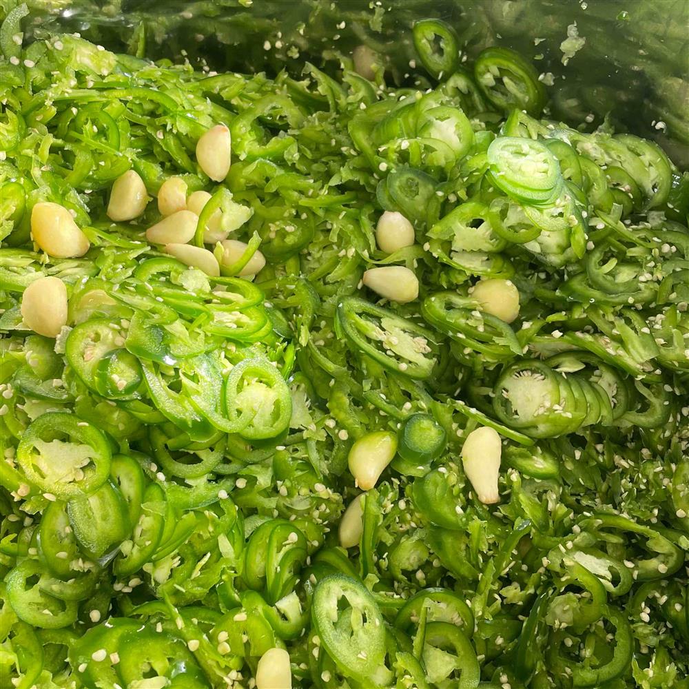 Sliced green jalapeños in liquid.
