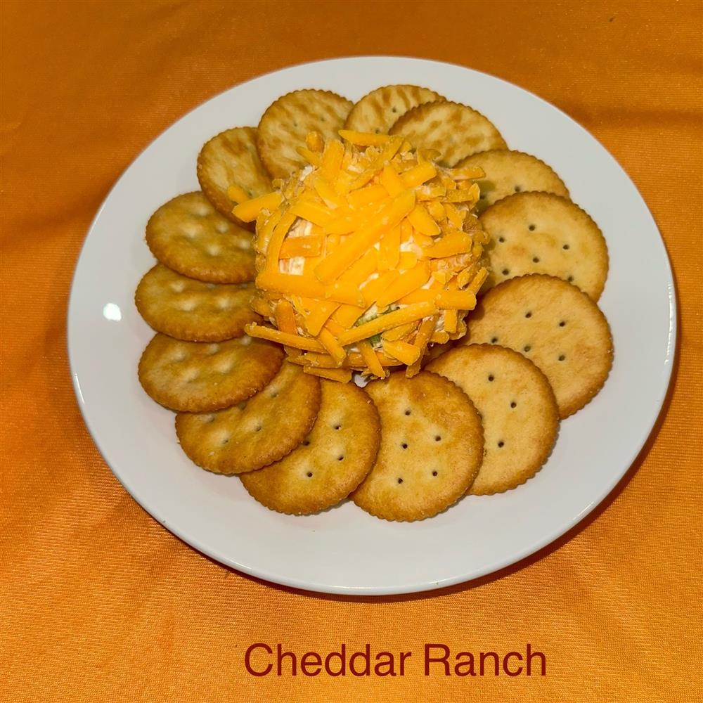 Cheeseball topped with shredded cheese and surrounded by crackers