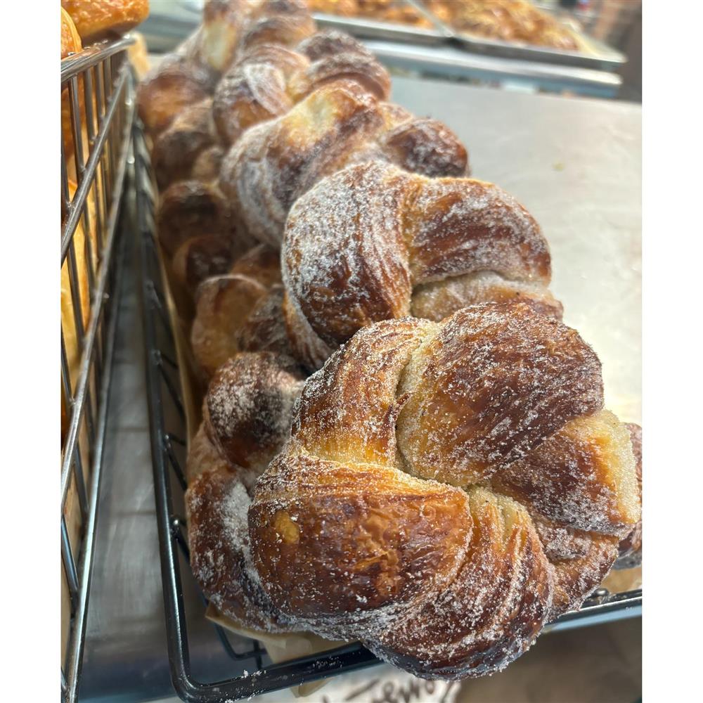 Twisted pastries dusted with sugar on a bakery rack.