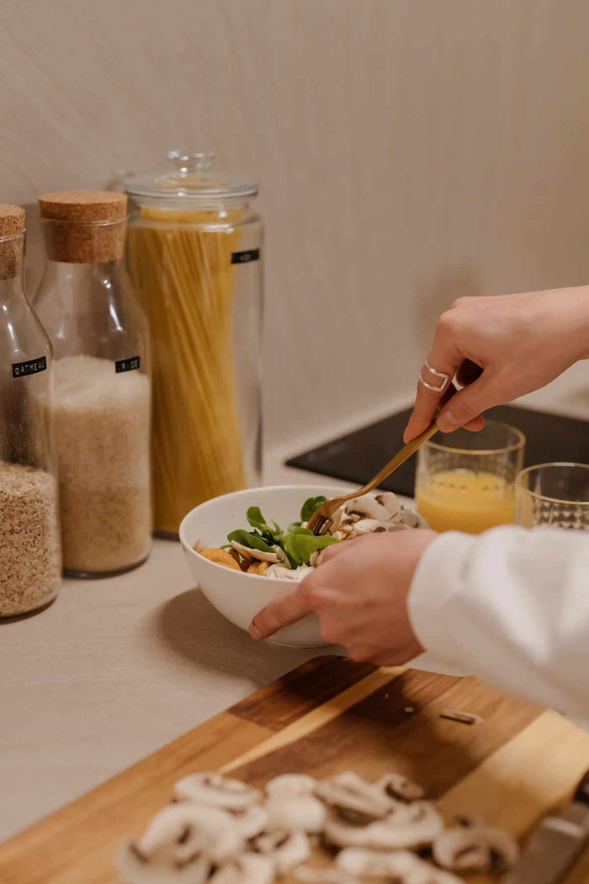 Hands preparing mushrooms and greens in a home kitchen.